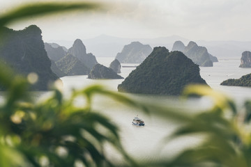 Tourist cruise ship sailing among limestone mountains in Halong Bay, Vietnam