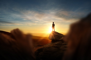 leadership and goals. a man standning on top of a mountain watching the sun set. conceptual photo co