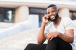 © Prostock-studio - Shy african guy with white smile talking on phone with happiness