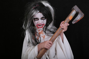 halloween horror concept. cute little scary girl in monster zombie costume with blood axe on black b