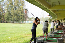 Asian Woman Practicing His Golf Swing At The Golf Driving Range.