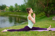 © Kate - Slender young brunette yogi performs complex yoga exercise on green grass in the summer on a background of nature