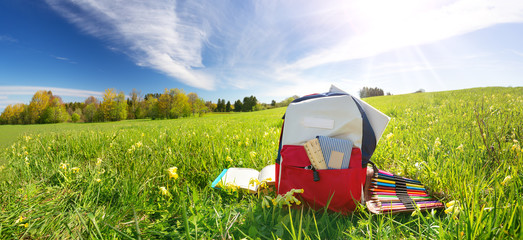 Colourful children schoolbag outdoors on the field