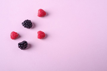 Raspberry and blackberry sweet organic juicy five berries on pink paper background, copy space