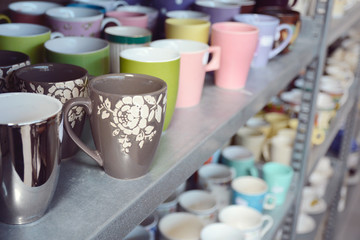 Second-hand mugs in metal storage rack for sale