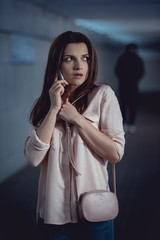 Wall Mural - selective focus of stressed woman talking on smartphone near thief in underpass