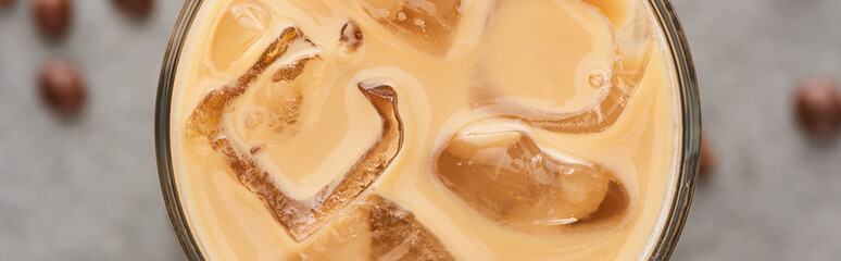 Wall Mural - close up view of ice coffee in glass with straw and coffee grains on grey background, panoramic shot