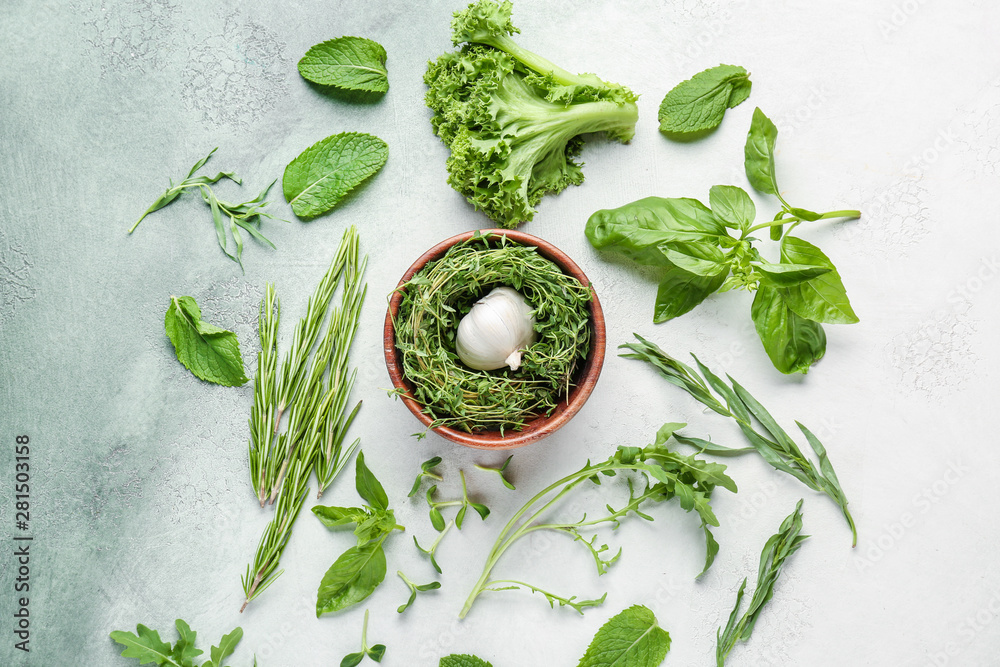 Different fresh herbs with garlic on color background