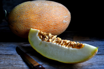 Sliced melon and knife on a wooden table.