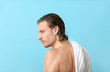 © Pixel-Shot - Handsome young man after washing hair against color  background