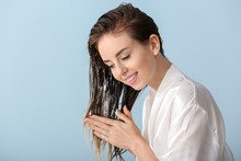 Beautiful Young Woman Applying Mousse On Her Hair After Washing Against Color Background