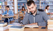 © JackF - Portrait of upset tired male student preparing for exam in university library