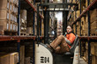 © Mint Images - Portrait of woman sitting in stock picker in distribution warehouse