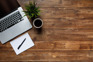 work space of a businessman. view from above . coffee black note and laptop on the desktop with black note. laptop on wooden background