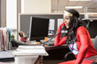 © Mint Images - Businesswoman in super hero costume working in office