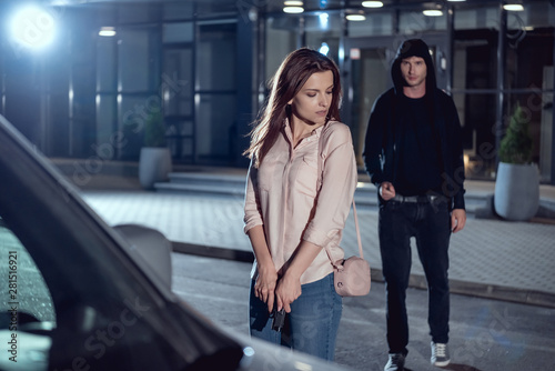 Fotografía woman with gun near thief at night in parking lot