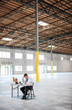 © Mint Images - Architect looking at blueprint while sitting in warehouse