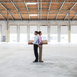 © Mint Images - Side view of man and woman holding cardboard boxes in warehouse