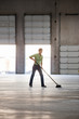© Mint Images - Woman sweeping up in warehouse