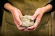 © Mint Images - Midsection of potter holding piece of pottery clay
