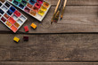 © LIGHTFIELD STUDIOS - top view of watercolor paint palettes and paintbrushes on wooden surface with copy space