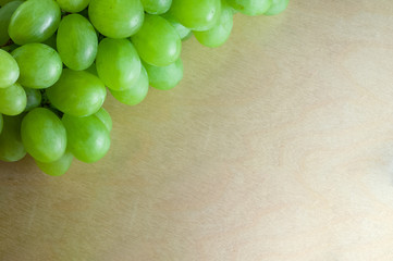 Green grapes on top of wooden textural surface. Close-up with copy space