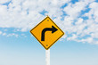 © Mint Images - Close up of caution turn ahead sign with cloudy sky