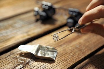 Wall Mural - Male jeweler evaluating precious gemstone at table in workshop, closeup