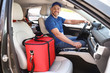 © New Africa - Male courier with thermo bag in car. Food delivery service
