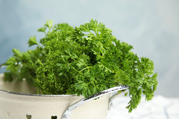 Colander with fresh green parsley against color background, closeup