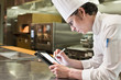 © Mint Images - Chef working on digital tablet in commercial kitchen