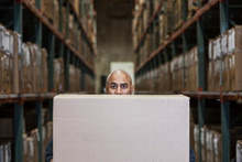 Portrait Of Worker Hiding Behind Cardboard Box In Warehouse