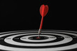 © New Africa - Red arrow hitting target on dart board against black background