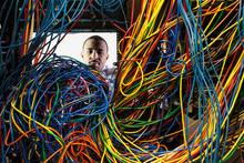 Technician working on tangled mess of cat 5 cables in server room