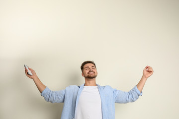 Sticker - Happy young man with air conditioner remote control on beige background