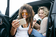 © Mint Images - Friends taking selfie while sitting in car