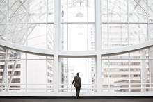 Rear View Of Businessman Looking Through Window In Convention Center