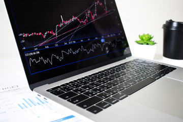 Poster - The laptop computer screen shows financial charts and graphs in the office.