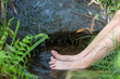 Kind kühlt seine nackten Füße in kaltem frischem Quellwasser eines kleinen Baches im Sommer und genießt die kühle Erfrischung