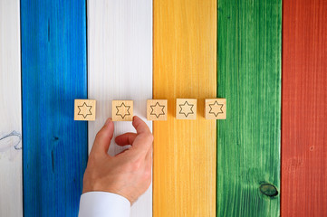 Wall Mural - man placing five wooden cubes with stars on them on colorful desk