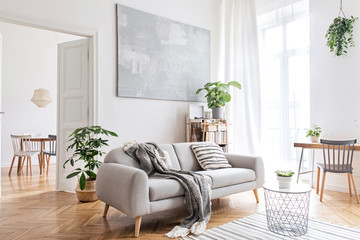 stylish scandinavian living room with design furniture, plants, bamboo bookstand and wooden desk. br