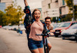 canvas print picture - Young couple on vacation having fun driving electric scooter through the city.	
