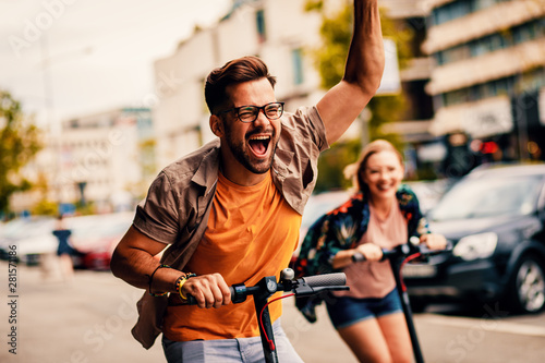Fotografía Young couple on vacation having fun driving electric scooter through the city