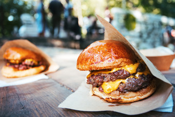 Street food festival background. Burgers close-up on the wooden table and people shown with a low-depth of field.