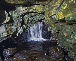 Geological rock formations and waterfall in an underground cave