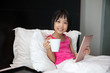 Leinwandbild Motiv Asian Little Chinese Girl playing tablet in bed