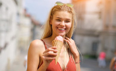 Wall Mural - a sunny girl in a summer dress eats ice cream and walks around the streets of the town