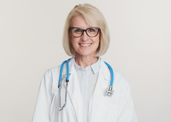 Friendly senior woman doctor is smiling. Isolated on white