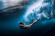 © artifirsov - Woman swim underwater with ocean wave.