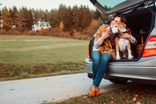 Woman With Dog Sit Together In Cat Truck And Warms цшер Hot Tea. Auto Travel With Pets Concept Image.